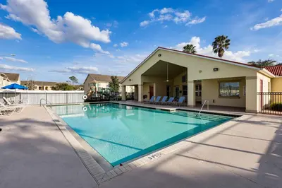 a swimming pool in front of a house at 5 Mi to WDW! Spacious Resort Escape with Pool Access in Kissimmee