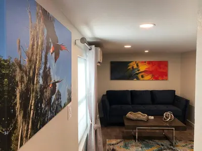 a living room with a blue couch and a painting at Charming Lakefront Cottage Near Disney in Orlando