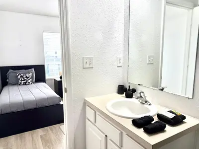 a bathroom with a sink and a mirror and a bed at Affordable Suite Near Disney World, Universal Studios & SeaWorld in Orlando
