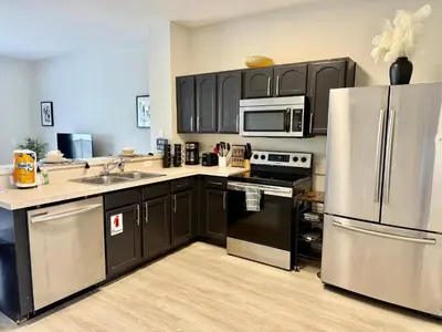 a kitchen with black cabinets and stainless steel appliances at Affordable Suite Near Disney World, Universal Studios & SeaWorld in Orlando