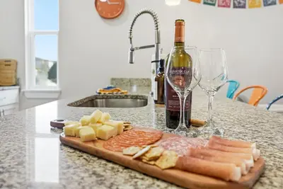 a cutting board with cheese and a bottle of wine at Casita Coco - Private Pool - Foosball - BBQ in Kissimmee