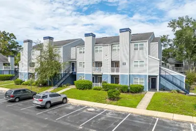 an apartment building with cars parked in a parking lot at Modern 1BR with Premium Finishes in Orlando
