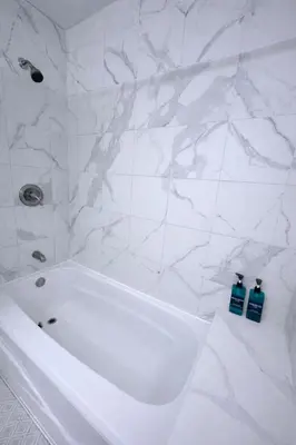 a white bath tub in a bathroom with marble walls at Family Retreat - 9 Min from Disney in Kissimmee