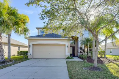 a house with a garage and palm trees at Fish and Boat Lake Toho Family Gem Near Theme Parks in Kissimmee