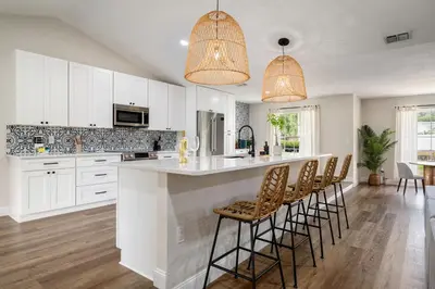 a kitchen with white cabinets and a large island with bar stools at Spacious home w screened patio & EV charger in Orlando