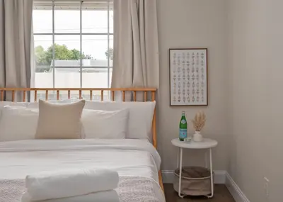 a white bedroom with a bed and a table at Spacious home w screened patio & EV charger in Orlando