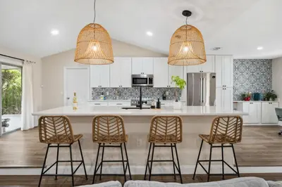 a kitchen with a large island with three bar stools at Spacious home w screened patio & EV charger in Orlando