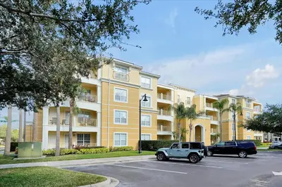a large yellow building with cars parked in a parking lot at Epic Universe Condo - Vista Cay - 2028 in Orlando