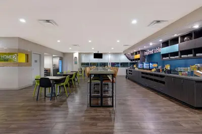a restaurant with a counter and tables and chairs at Home2 Suites by Hilton Orlando International Drive South - Free Shuttle to Theme Parks in Orlando