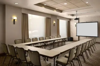 a conference room with tables and chairs and a white screen at Hampton Inn & Suites Orlando/Downtown South - Medical Center in Orlando