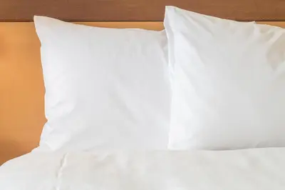 a bed with white sheets and pillows on it at Staybridge Suites Orlando at SeaWorld by IHG - Free Breakfast & Shuttle to SeaWorld Parks in Orlando