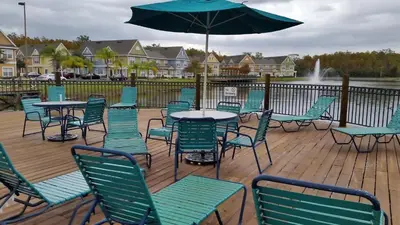 a deck with tables and chairs and an umbrella at True Happiness, Housing Near Disney Word in Kissimmee