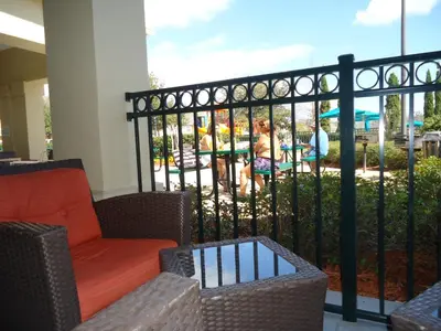 a balcony with chairs and a fence with a view of a pool at True Happiness, Housing Near Disney Word in Kissimmee