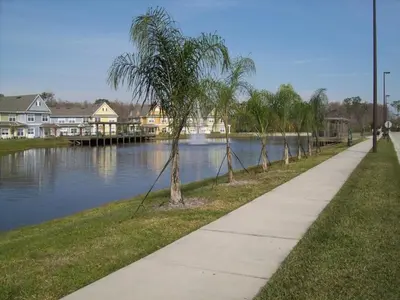 a sidewalk next to a river with palm trees at True Happiness, Housing Near Disney Word in Kissimmee