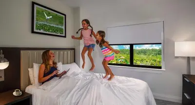 two little girls jumping on top of a bed at The Grove Resort & Water Park Orlando in Orlando