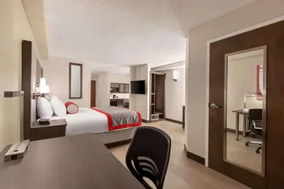 a hotel room with a bed and a desk at Ramada by Wyndham Suites Orlando Airport- Free Airport Shuttle in Orlando