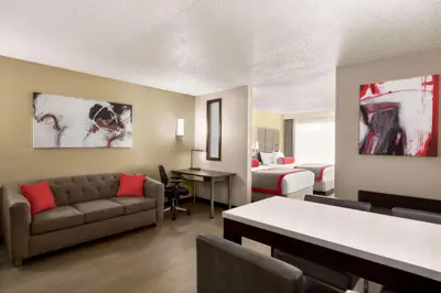 a living room with a couch and a bed at Ramada by Wyndham Suites Orlando Airport- Free Airport Shuttle in Orlando