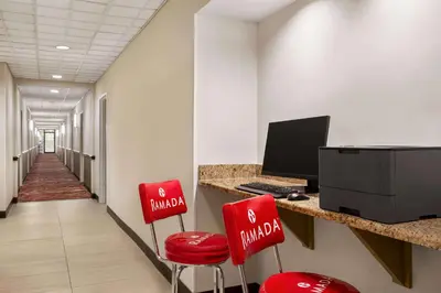 a corridor with two red chairs and a desk with a computer at Ramada by Wyndham Suites Orlando Airport- Free Airport Shuttle in Orlando
