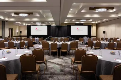 a conference room with tables and chairs and two screens at Marriott Orlando Airport Lakeside in Orlando