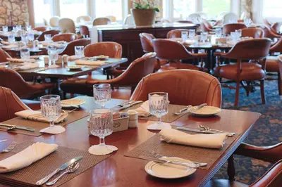 a dining room with tables and chairs with glasses and napkins at Arnold Palmer's Bay Hill Club & Lodge in Orlando