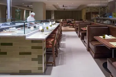 a restaurant with a long bar with wooden tables and chairs at Hyatt Regency Orlando International Airport Hotel in Orlando