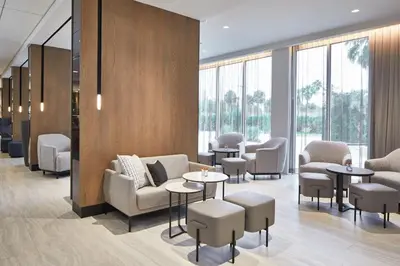 a waiting room with chairs and tables and windows at AC Hotel by Marriott Orlando Lake Buena Vista in Orlando