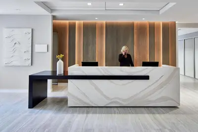 a woman standing behind a reception desk in a lobby at AC Hotel by Marriott Orlando Lake Buena Vista in Orlando