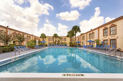 a large swimming pool with chairs in front of a building at La Quinta Inn by Wyndham Orlando International Drive North in Orlando