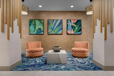 a lobby with two chairs and a table and paintings at Hyatt Place Orlando / I-Drive / Convention Center in Orlando