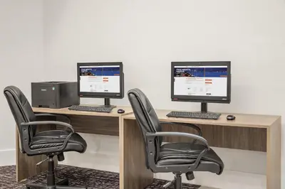 two computer monitors sitting on a desk with chairs at Crowne Plaza Orlando - Lake Buena Vista by IHG in Orlando