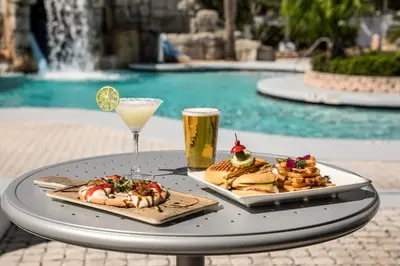a tray of food and a drink on a table by a pool at Crowne Plaza Orlando - Lake Buena Vista by IHG in Orlando