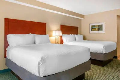 two beds in a hotel room with white sheets at Holiday Inn Resort Orlando - Lake Buena Vista by IHG in Orlando