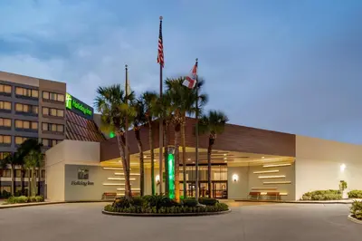 a hotel with palm trees in front of a building at Holiday Inn Orlando International Airport by IHG in Orlando