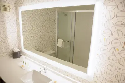 a bathroom with a large mirror over a sink at Holiday Inn Orlando International Airport by IHG in Orlando