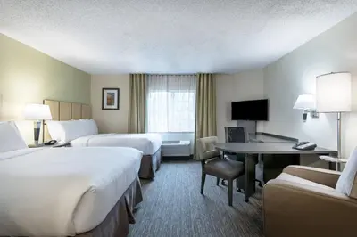 a hotel room with two beds and a desk at Candlewood Suites Lake Mary by IHG in Lake Mary