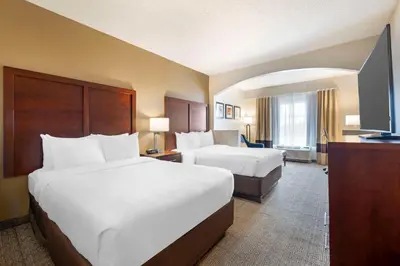 a hotel room with two beds and a flat screen tv at Comfort Suites Downtown in Orlando