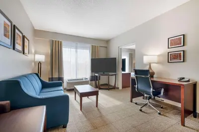 a hotel room with a blue couch and a desk at Comfort Suites Downtown in Orlando
