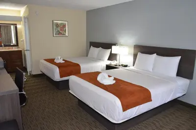 a hotel room with two beds with towels on them at Days Inn & Suites by Wyndham Orlando Airport in Orlando