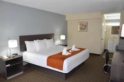 a hotel room with a bed with towels on it at Days Inn & Suites by Wyndham Orlando Airport in Orlando