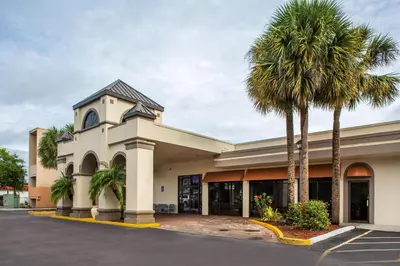 a building with palm trees in front of it at Days Inn & Suites by Wyndham Orlando Airport in Orlando