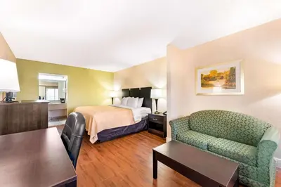 a hotel room with a bed and a couch and a table at Quality Inn & Suites Orlando Airport in Orlando