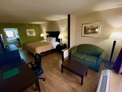 a hotel room with a bed and a couch and a chair at Quality Inn & Suites Orlando Airport in Orlando