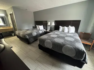 a hotel room with two beds and a chair at Budget Inn Sanford International Airport in Sanford