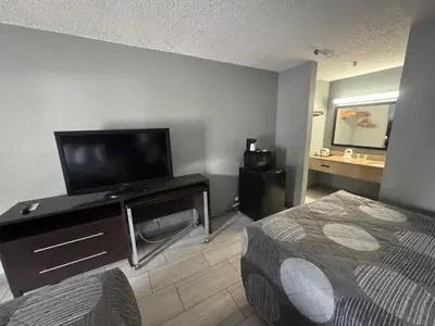 a hotel room with a bed and a flat screen tv at Budget Inn Sanford International Airport in Sanford