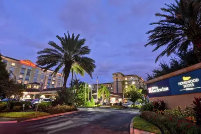 a street in front of a hotel with palm trees at Hilton Garden Inn Orlando Lake Buena Vista in Orlando