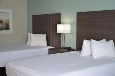 two beds in a hotel room with white pillows at Opal Hotel & Suites in Orlando