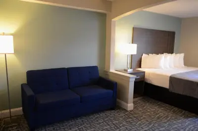 a hotel room with a bed and a blue chair at Opal Hotel & Suites in Orlando