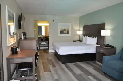 a hotel room with a bed and a desk and a chair at Opal Hotel & Suites in Orlando