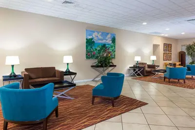 a waiting room with blue chairs and a painting on the wall at Ramada by Wyndham Kissimmee Gateway - Free Theme Park Shuttle in Orlando