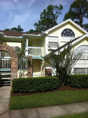 a white house with a porch and an archway at Villas at Laguna Bay in Kissimmee